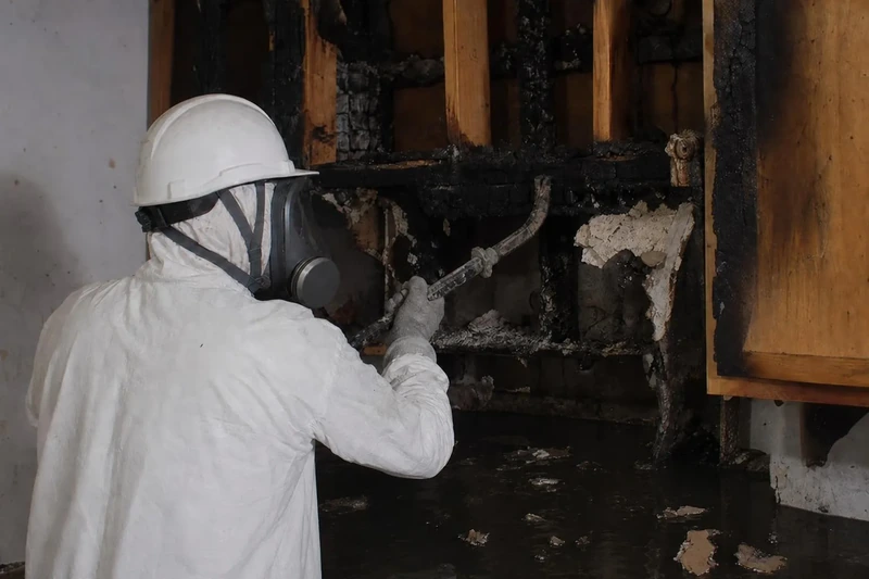 Charred ceiling joists and fallen debris lying in standing suppression water in a Salt Lake City house