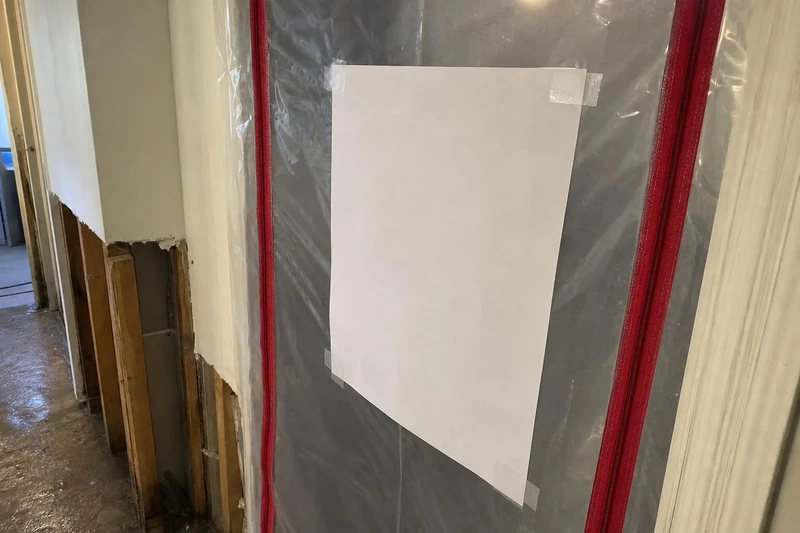 Independent assessor's scope taped to the outside of a sealed containment door in a Salt Lake City home