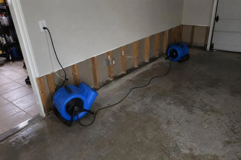 Air moving from two fans reaches into the cut-open wall of a Draper garage, where bare studs stand exposed