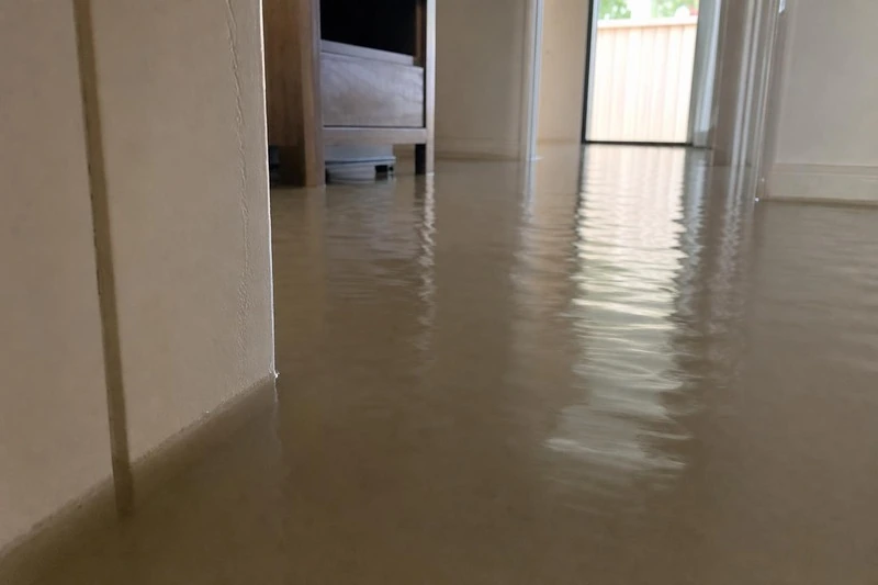 Water stands over the carpet of a Sandy lower floor, high enough to swallow the feet of a media cabinet against the wall